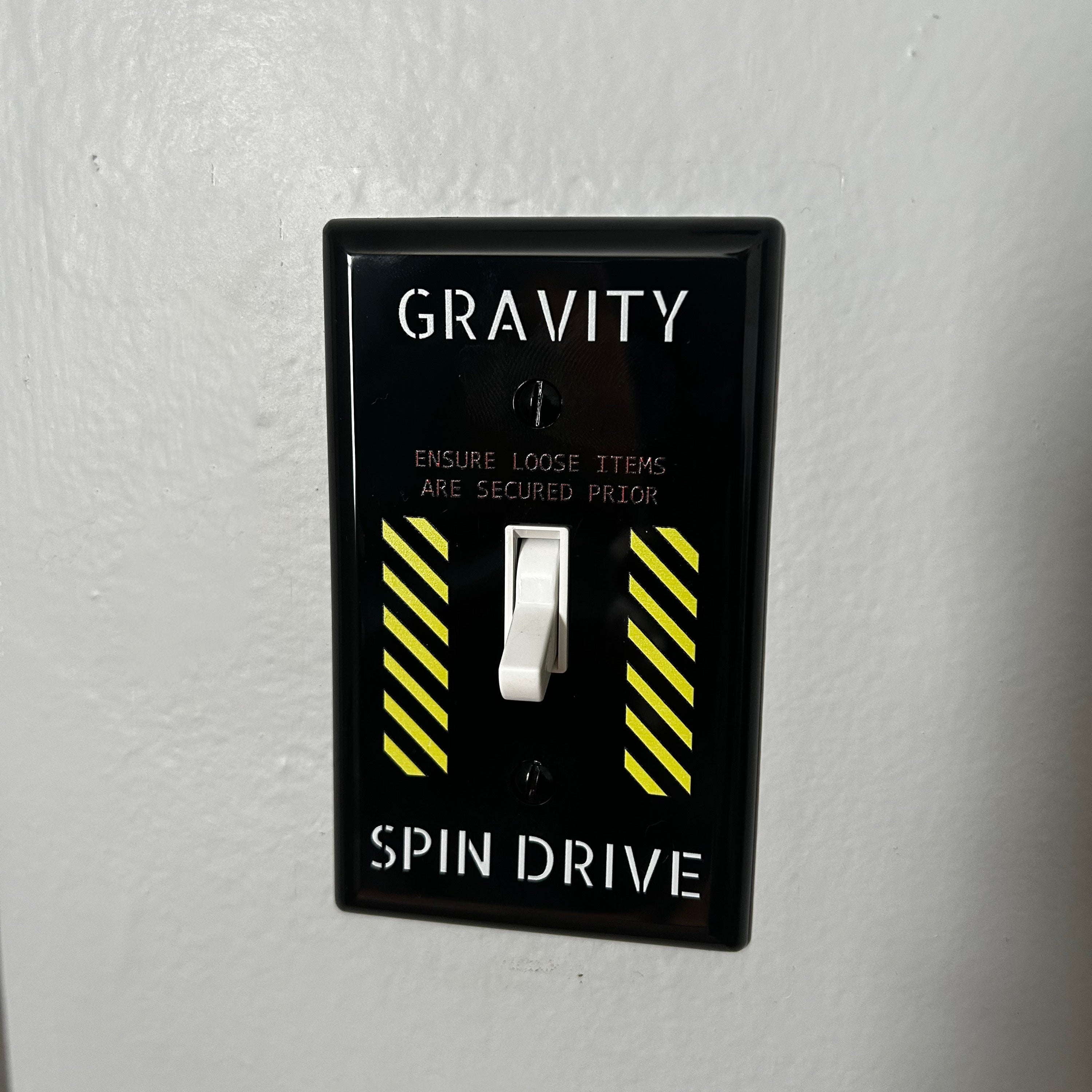 Light switch with 'Gravity' and 'Spin Drive' labels on a gray wall.