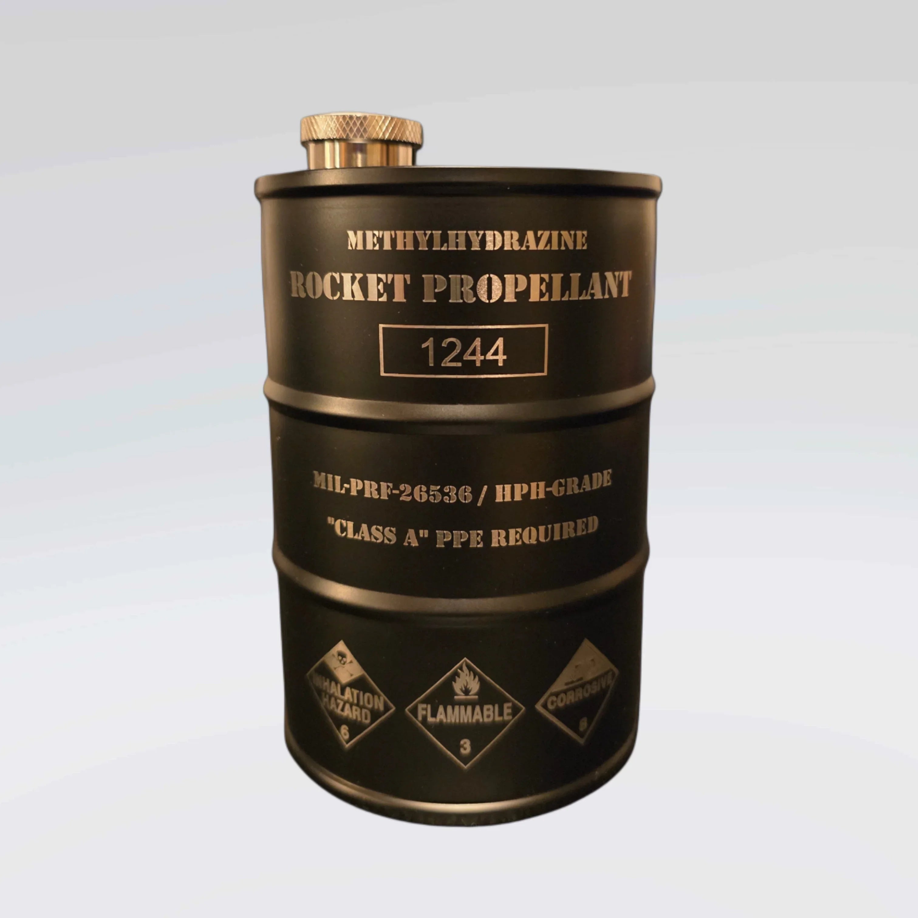 Black metal drum labeled methylhydrazine rocket propellant 1244 with hazard warnings