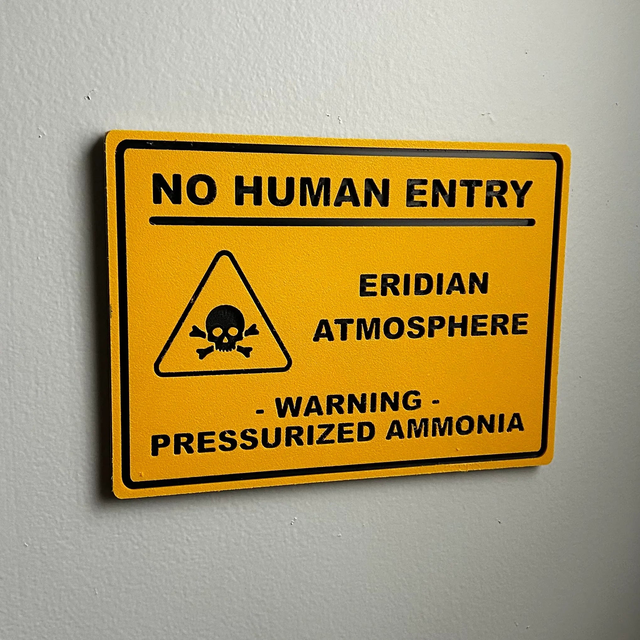 Yellow warning sign on wall with skull symbol and text no human entry, Eridian atmosphere, pressurized ammonia