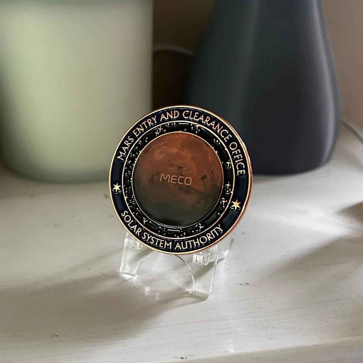 Round Mars Entry and Clearance Office coin with planet Mars image on clear stand on white surface