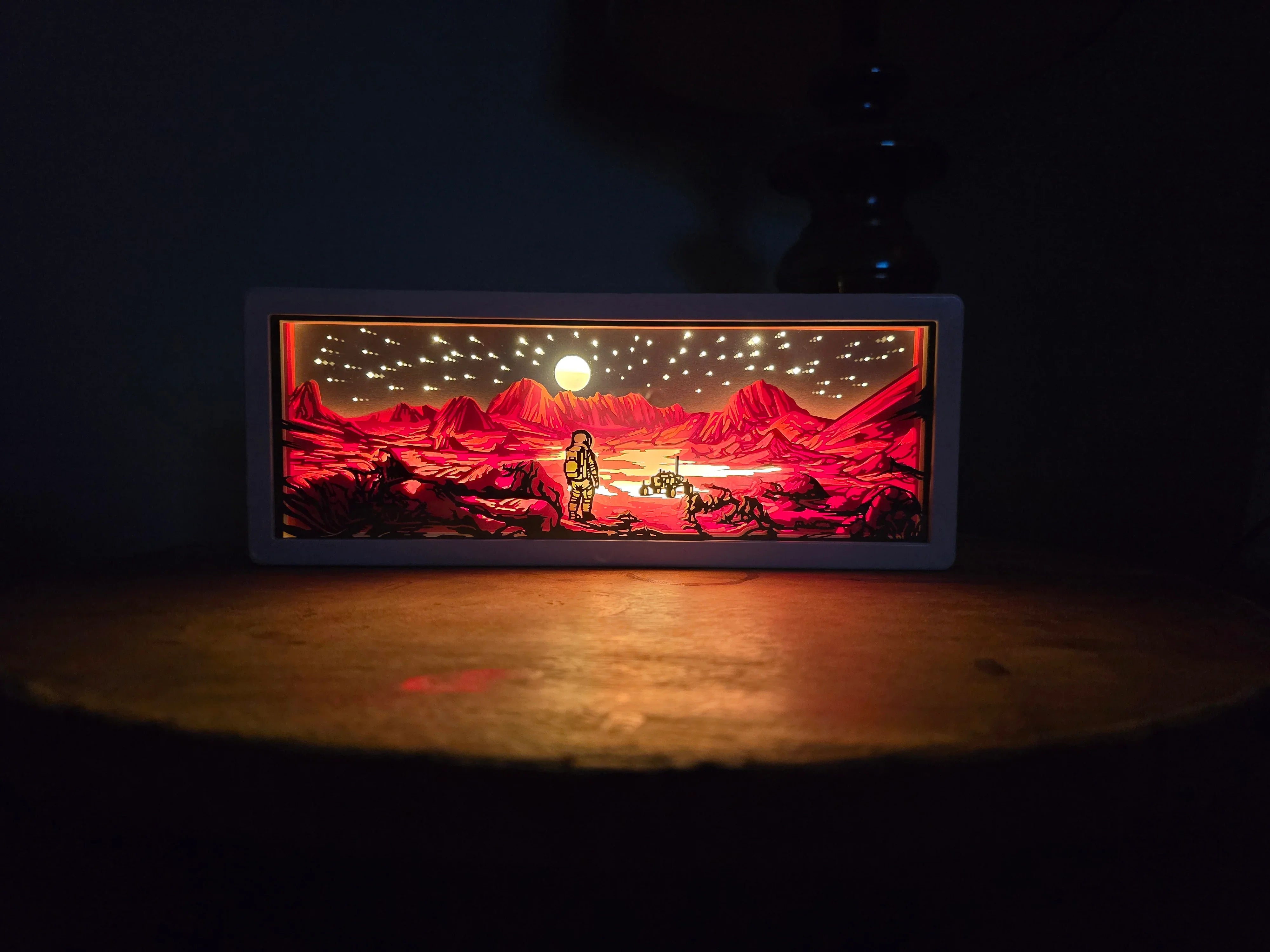 Illuminated space-themed shadow box art showing astronaut and rover on red alien landscape under starry sky