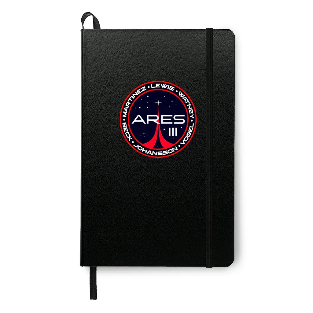 Black notebook with Ares III space mission patch featuring red and white design and astronaut names