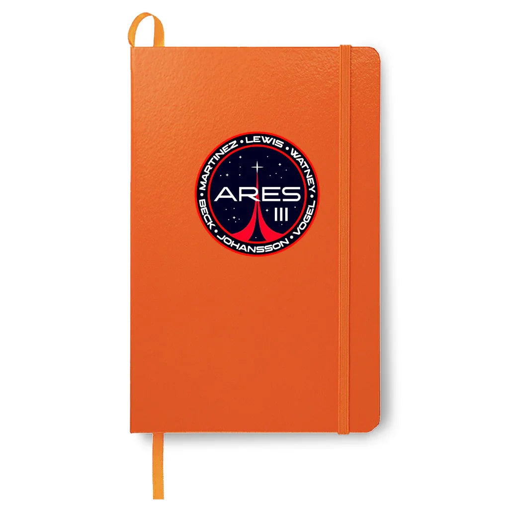 Orange notebook with elastic band and Ares III space mission patch featuring names and stars