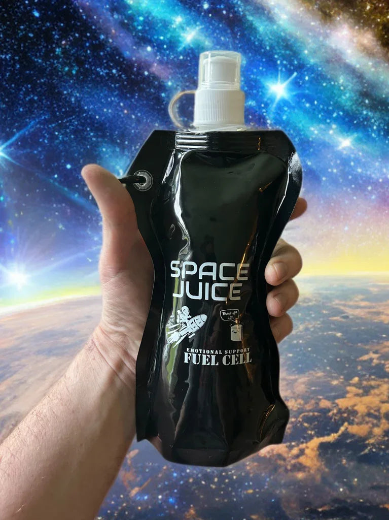 Hand holding black Space Juice pouch with spray cap and cosmic space background
