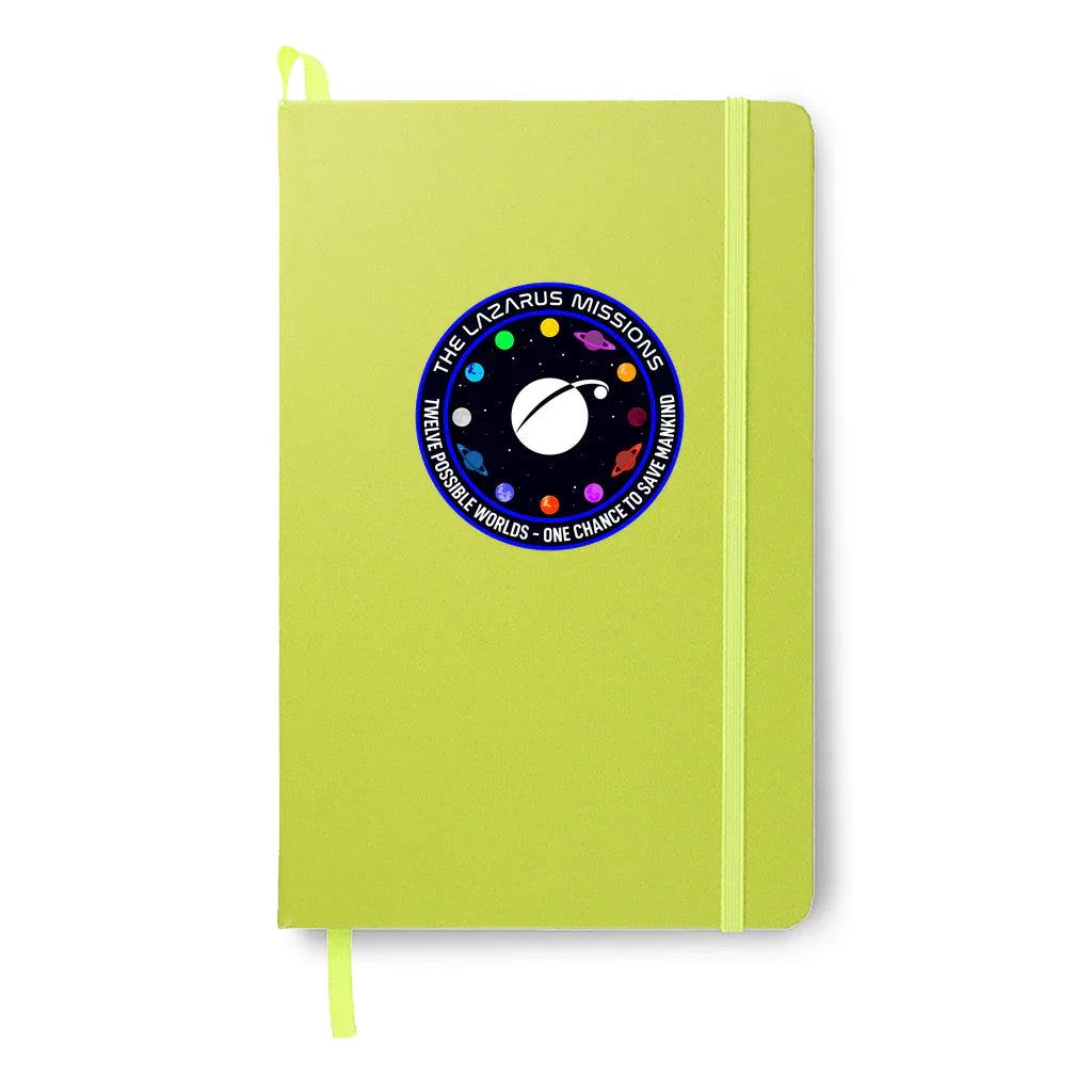 Lime green notebook with The Lazarus Missions space-themed patch showing planets and text