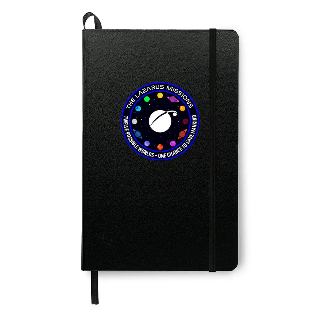 Black notebook with elastic band featuring circular Lazarus Missions space patch with planets and text
