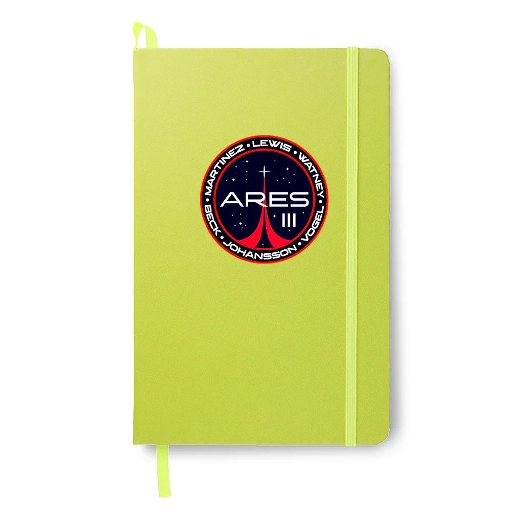Lime green notebook with Ares III mission patch featuring names Martinez, Lewis, Watney, Beck, Johansson, Vogel