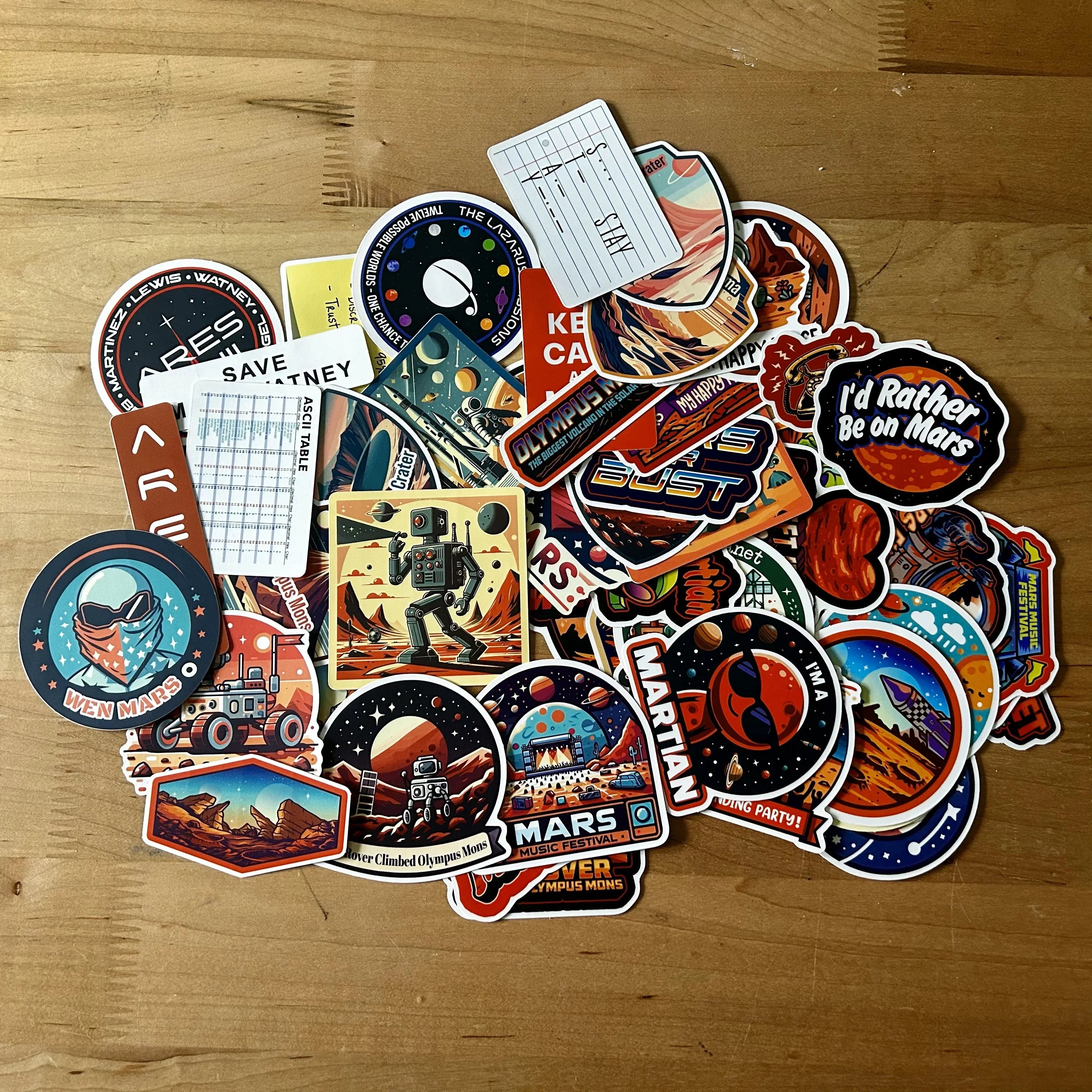 Collection of colorful Mars-themed stickers on wooden surface including robots, rovers, and space graphics