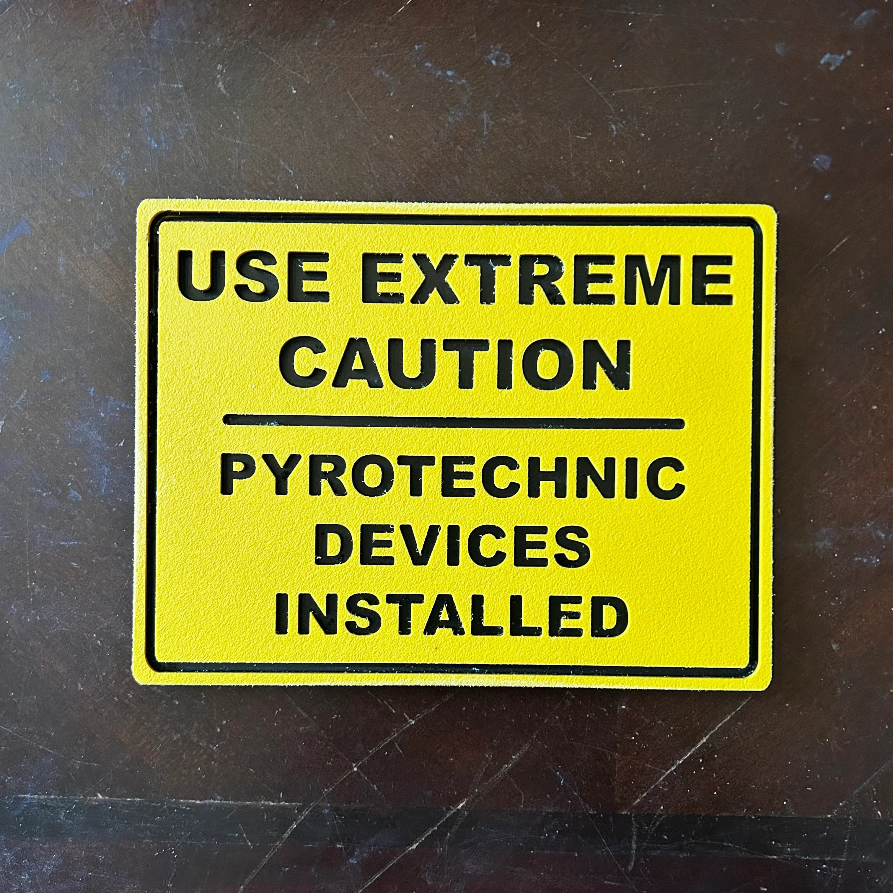 Yellow safety warning sign reading Use Extreme Caution Pyrotechnic Devices Installed