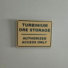 Tan sign on gray wall reading Turbinium Ore Storage Authorized Access Only