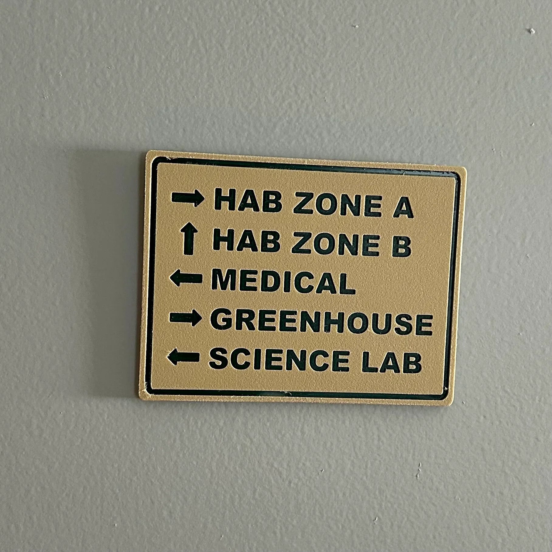 Directional sign on wall pointing to HAB Zone A, HAB Zone B, Medical, Greenhouse, and Science Lab