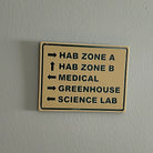 Directional sign on wall pointing to HAB Zone A, HAB Zone B, Medical, Greenhouse, and Science Lab