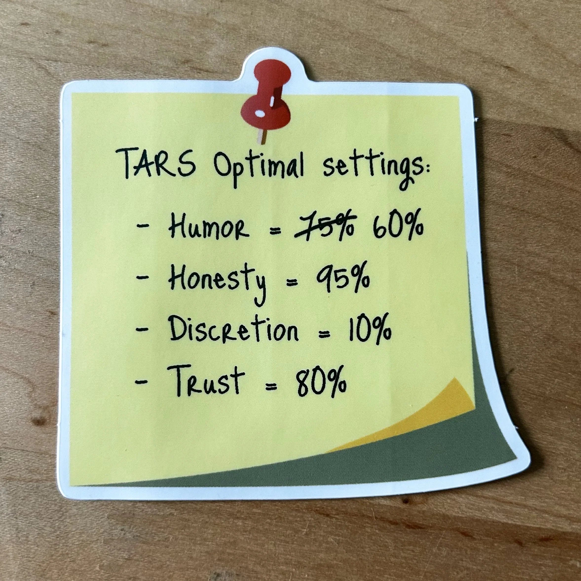 Yellow sticky note with TARS optimal settings for humor, honesty, discretion, and trust on wooden surface