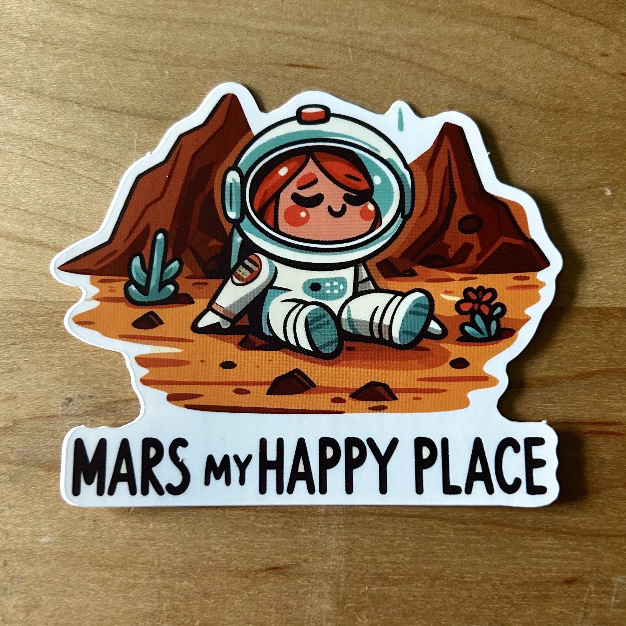 Sticker of a smiling cartoon astronaut sitting on Mars with rocky terrain and text Mars my happy place