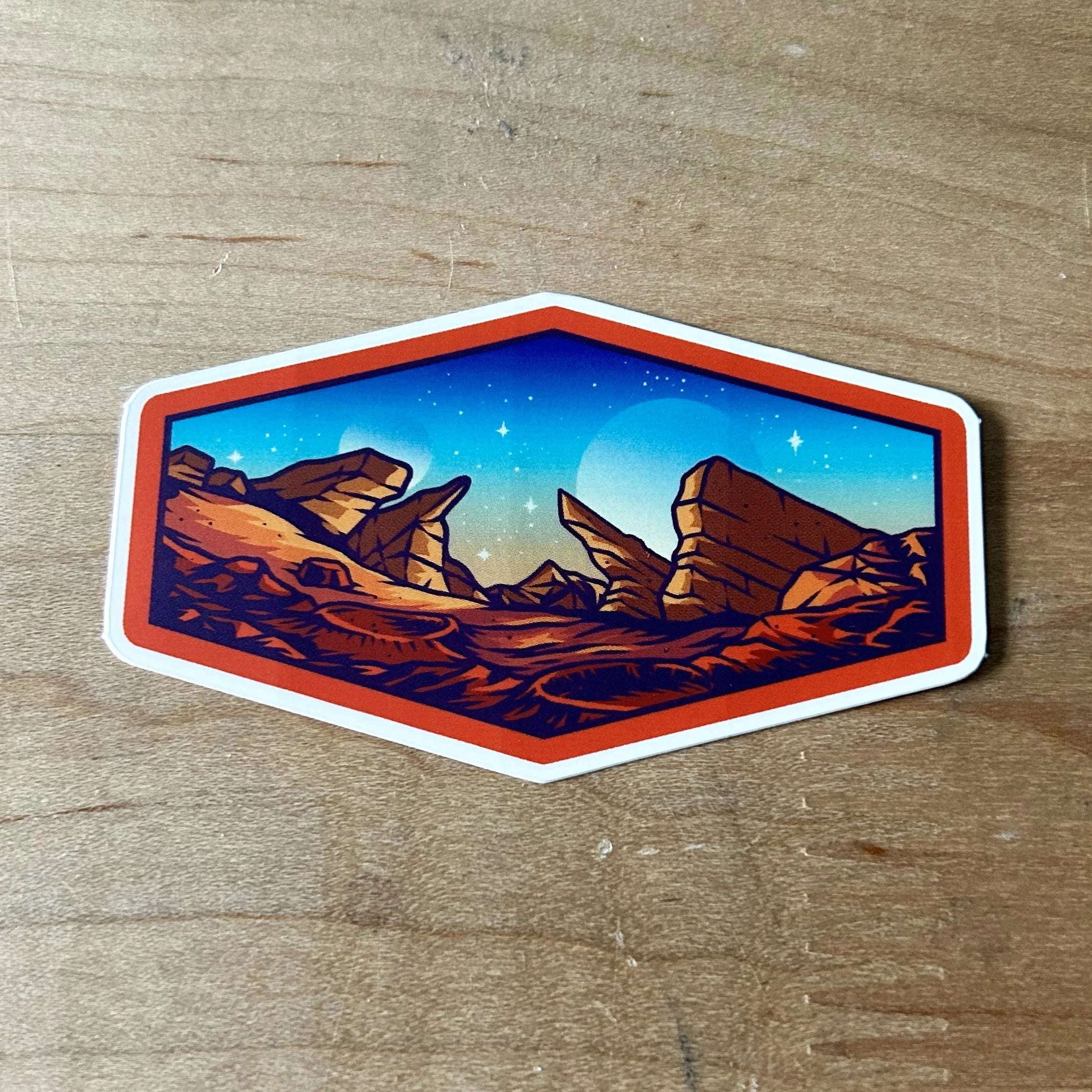 Hexagonal sticker of a desert landscape with red rock formations under a starry dusk sky