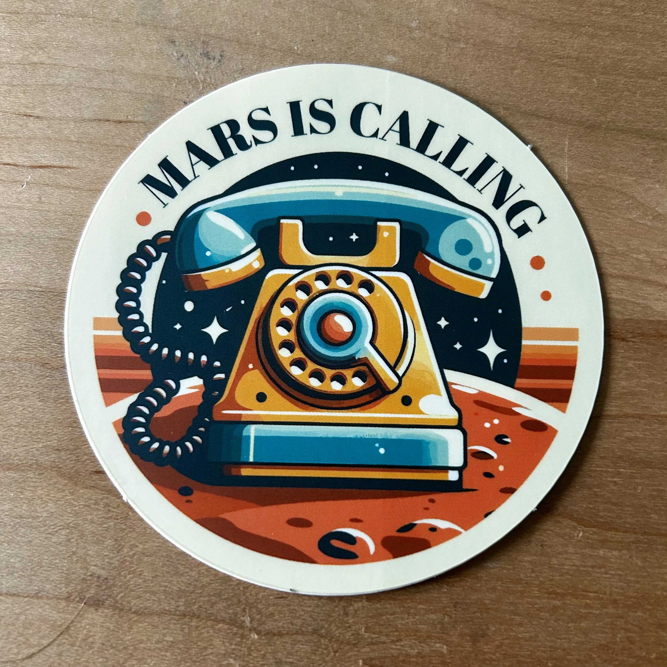 Round sticker with a vintage rotary phone on Mars surface and text Mars is Calling