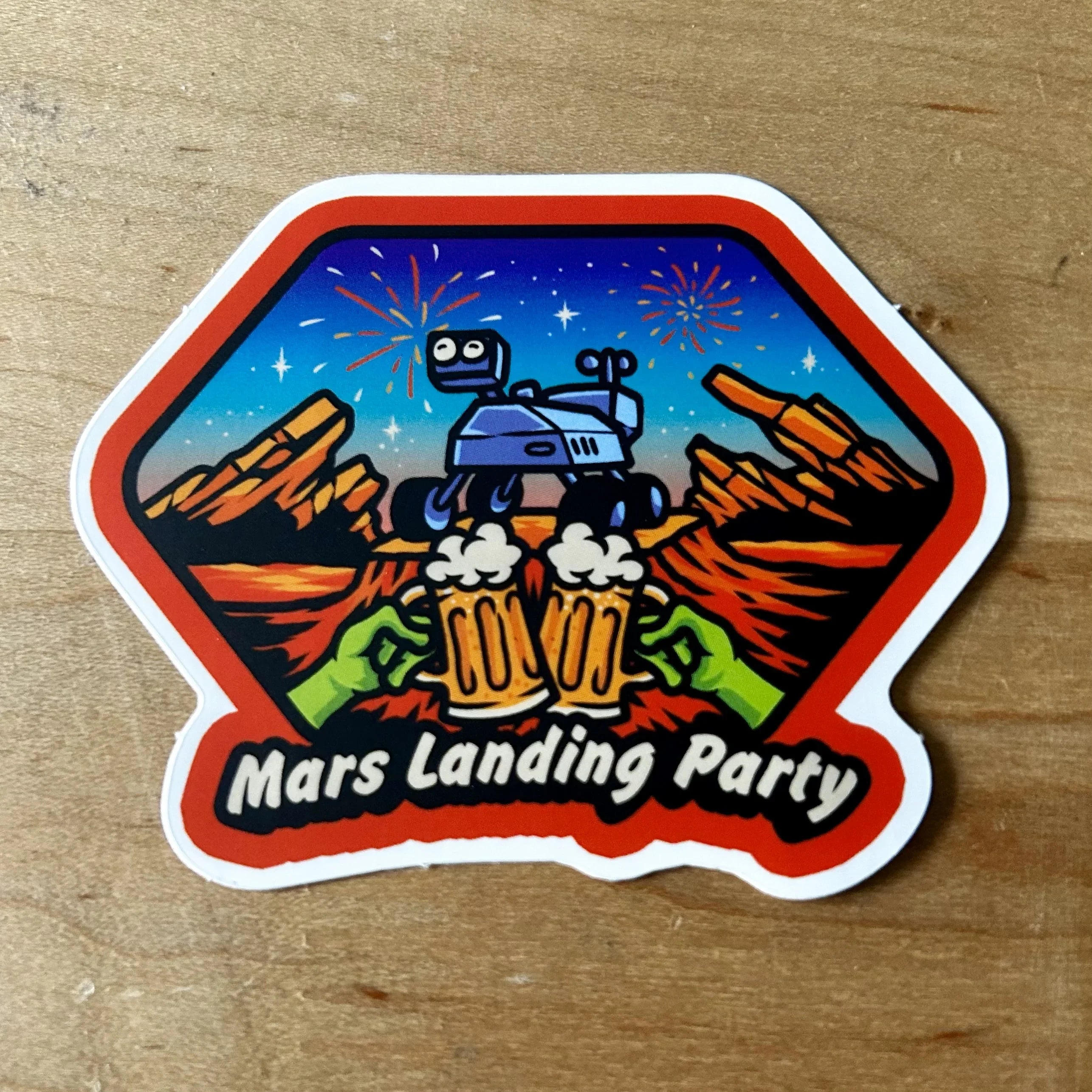 Sticker showing Mars landscape with rover, two green hands clinking beer mugs, fireworks, text Mars Landing Party