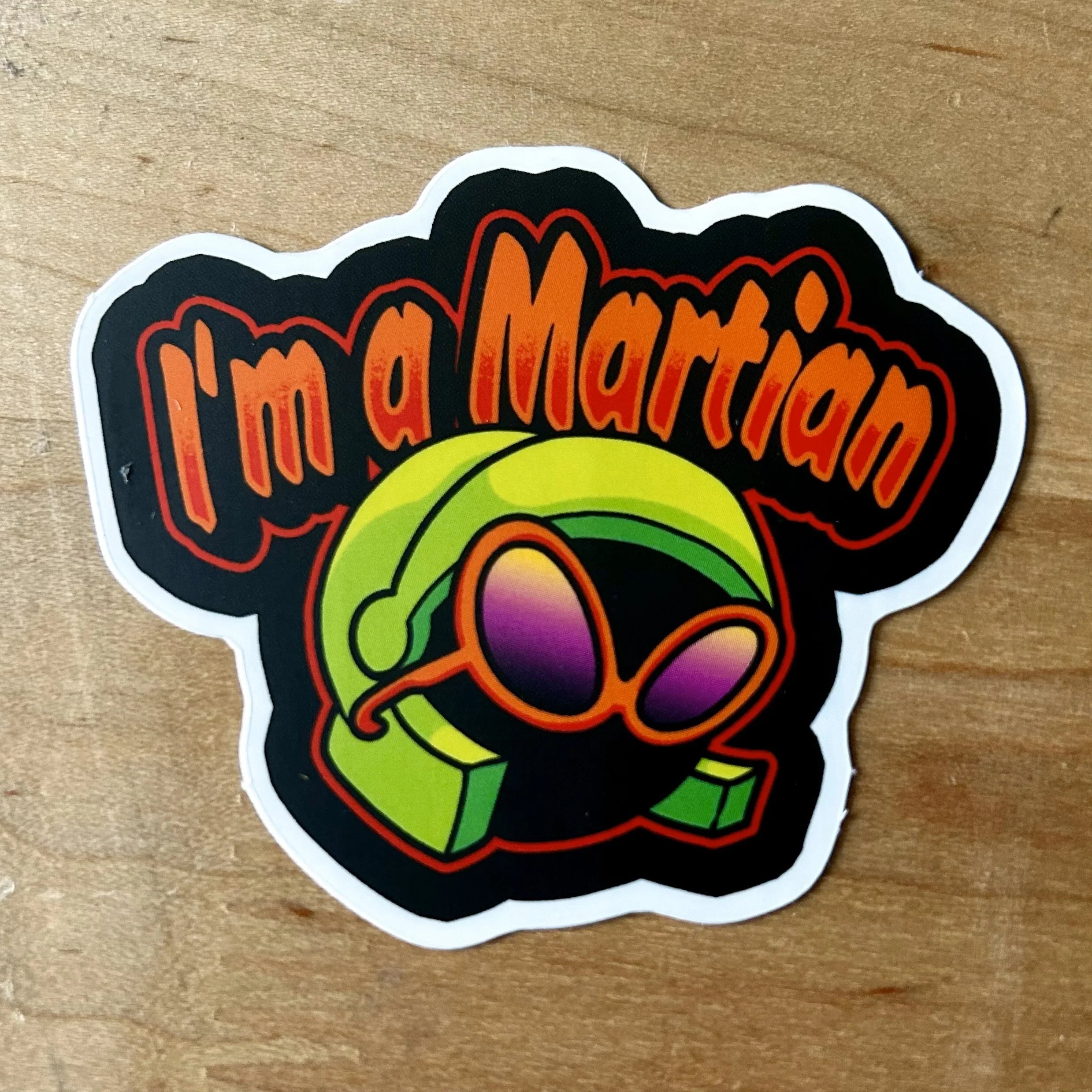 Sticker with cartoon alien wearing green helmet and purple sunglasses saying I'm a Martian