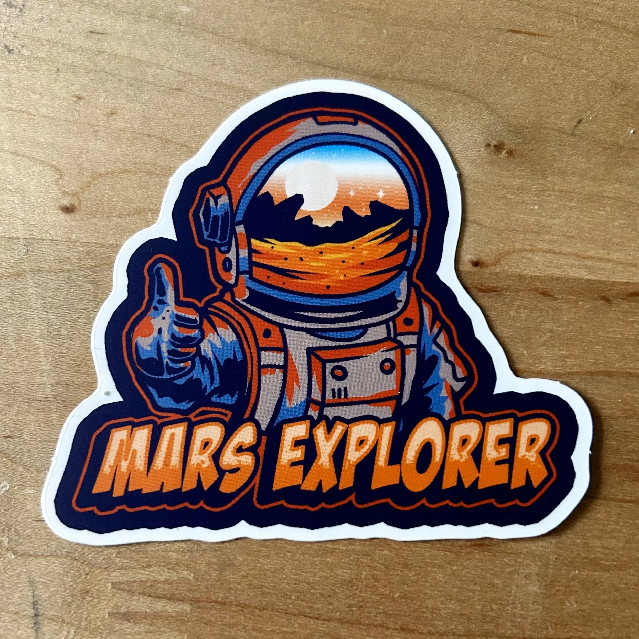 Sticker of an astronaut in orange suit giving thumbs up with Mars landscape reflection and text Mars Explorer
