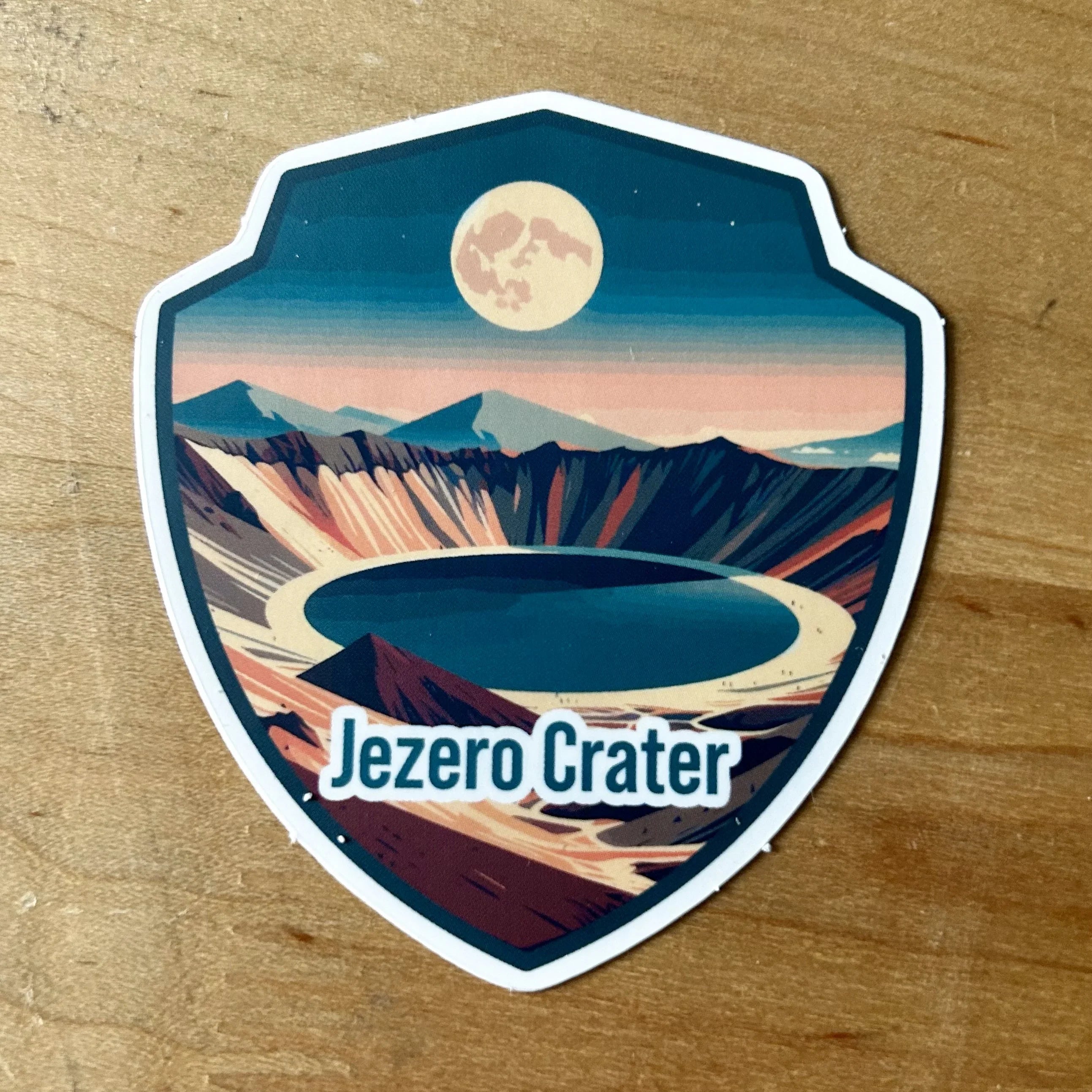 Illustrated shield logo featuring Jezero Crater with a full moon and desert mountains