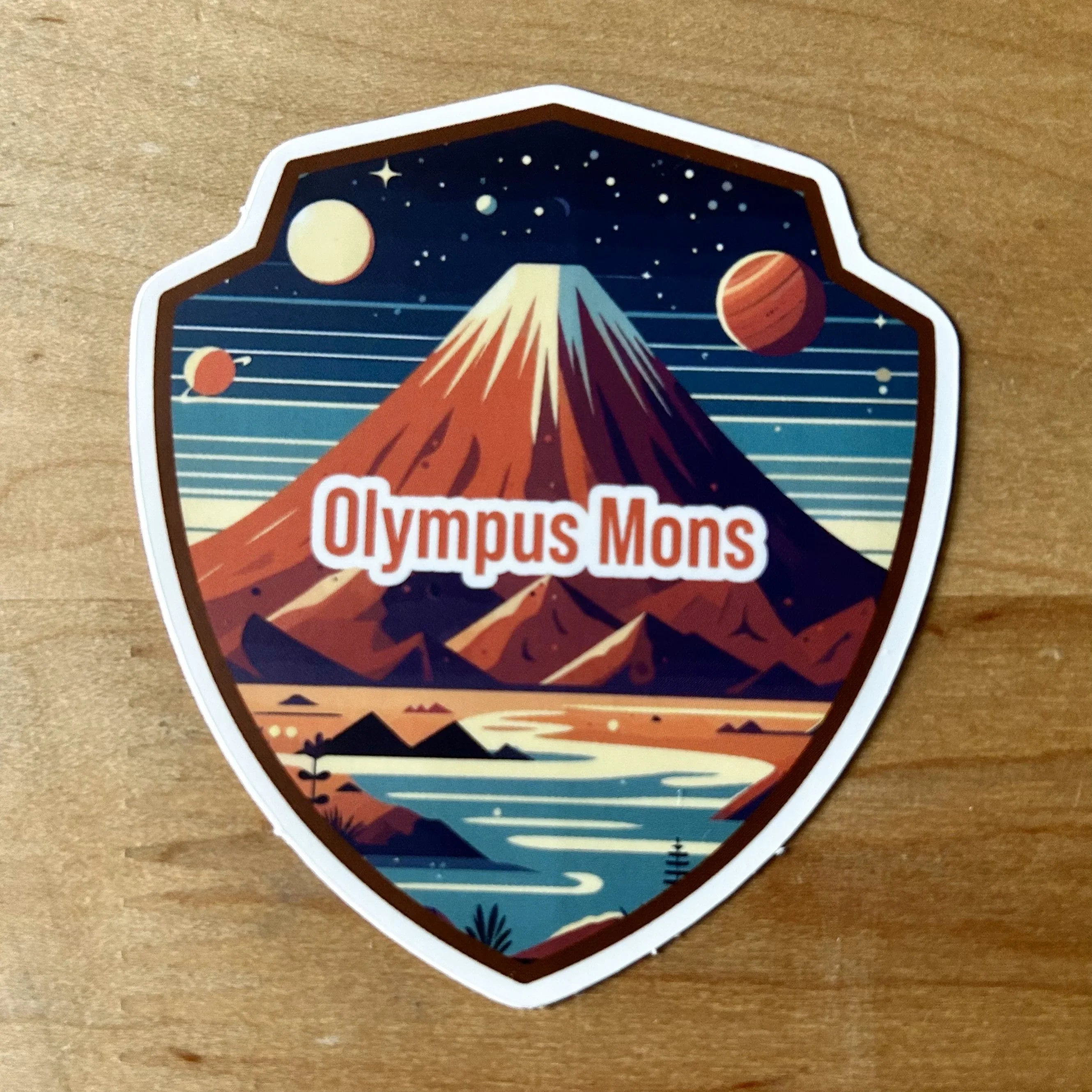 Shield-shaped sticker featuring Olympus Mons mountain with planets and stars in space background