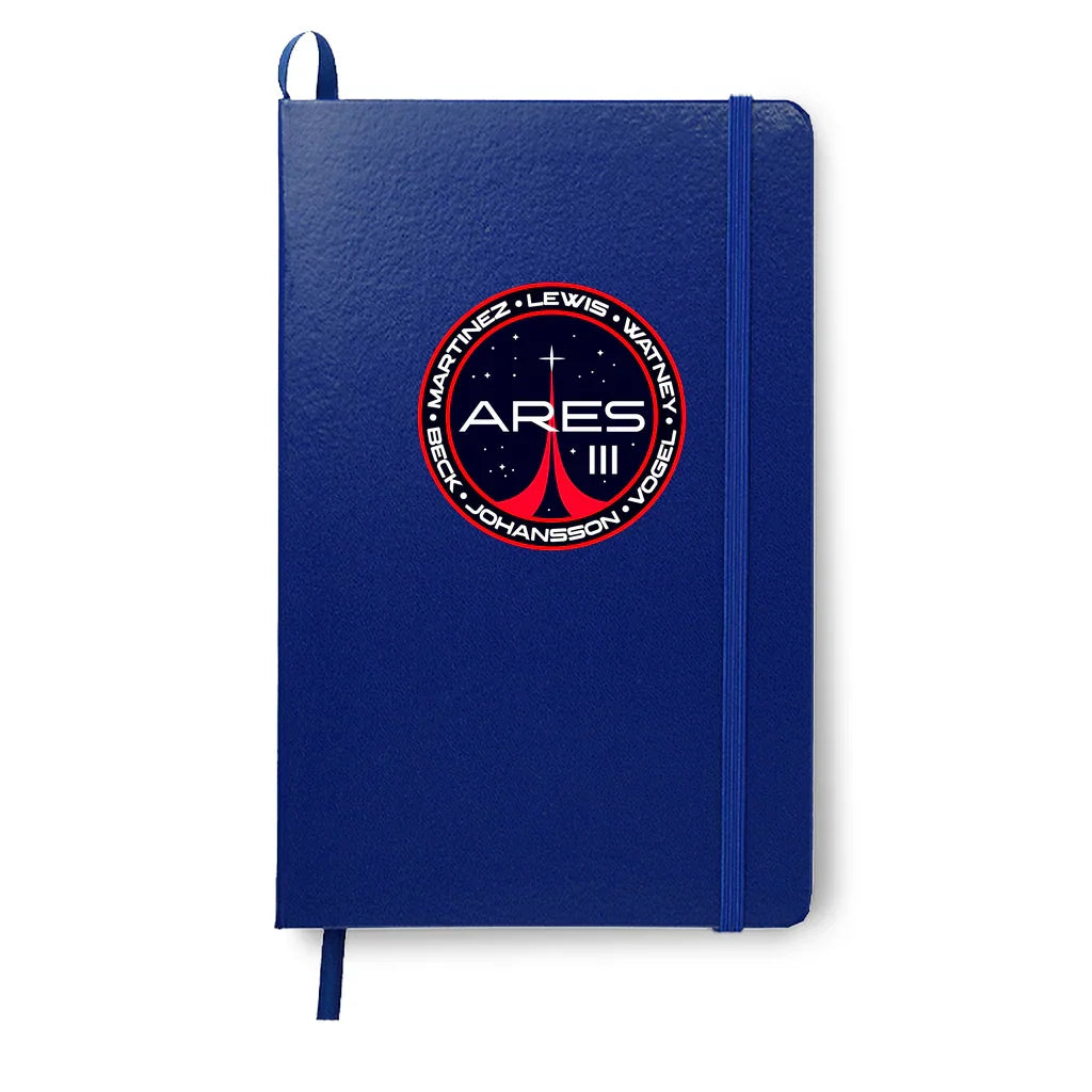 Blue hardcover notebook with Ares III space mission patch featuring names and stars