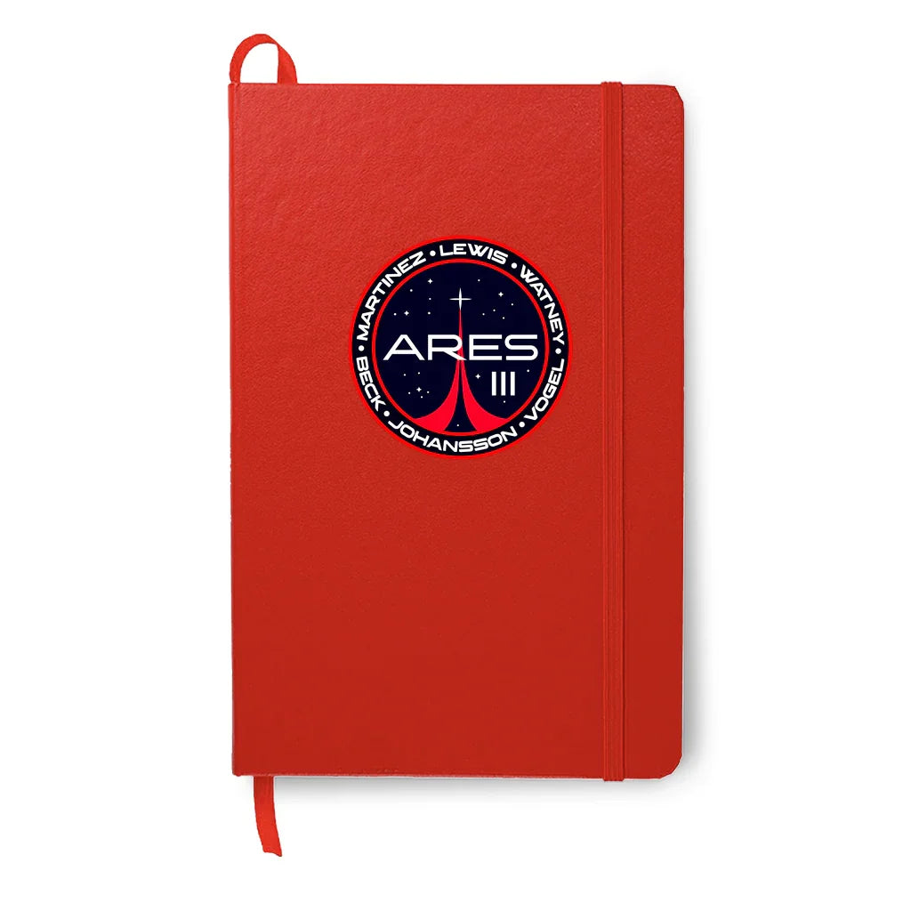 Red notebook with Ares III mission patch featuring astronaut names and space design