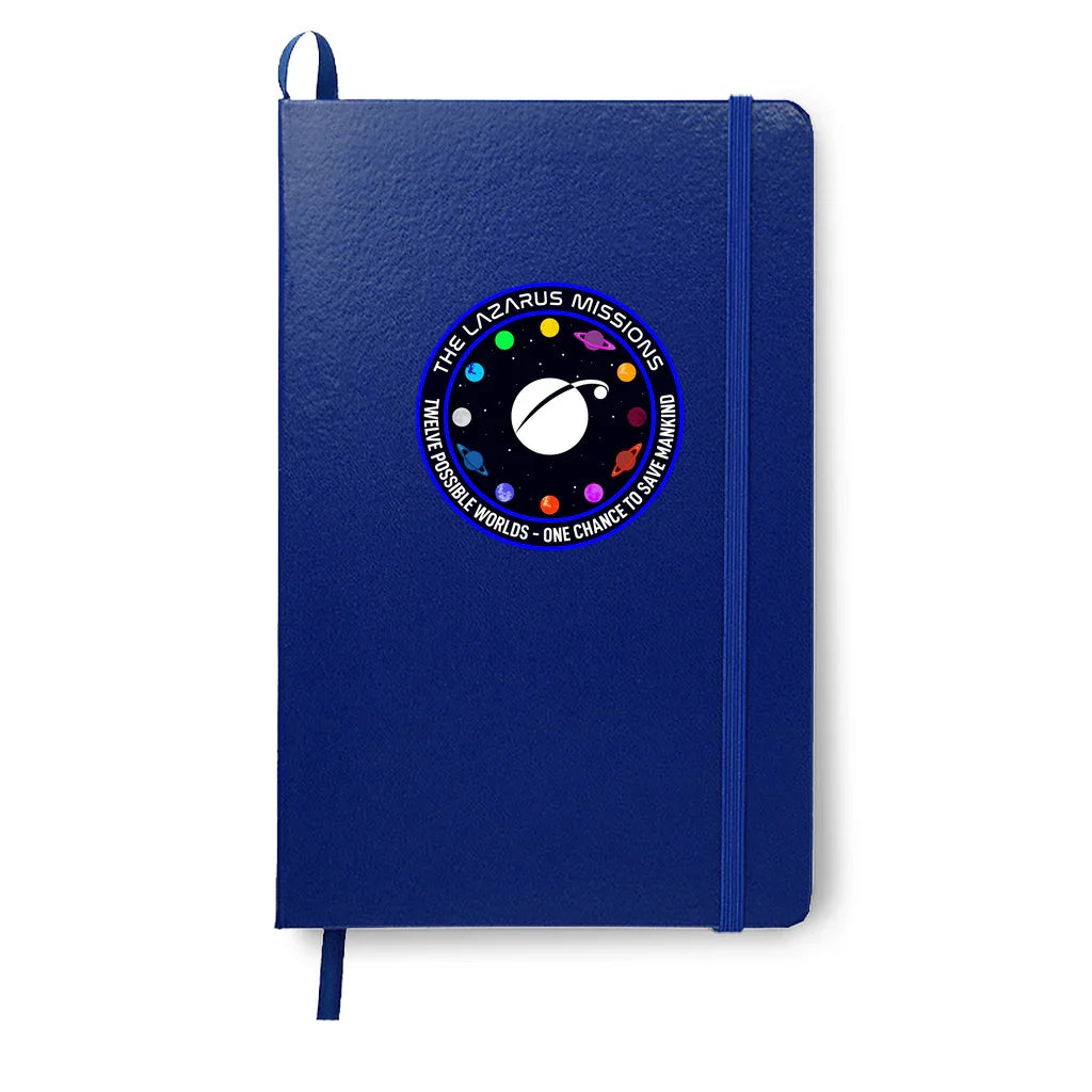 Blue notebook with elastic band and circular space mission patch featuring planets and text 'The Lazarus Missions'
